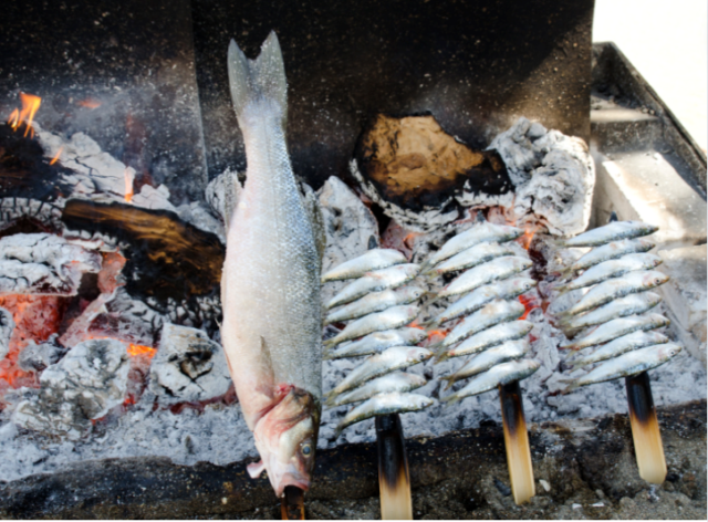 Fish and sardines on skewers cooking over an open fire