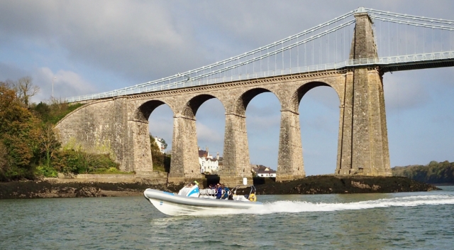 RibRide's Adventure RIB travelling along the Menai Strait, with Menai Bridge in the background