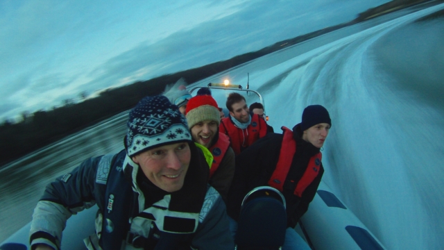 An Adventure RIB doing a turn out on the water in winter, taken from inside the boat with lots of smiling faces and people wearing warm hats